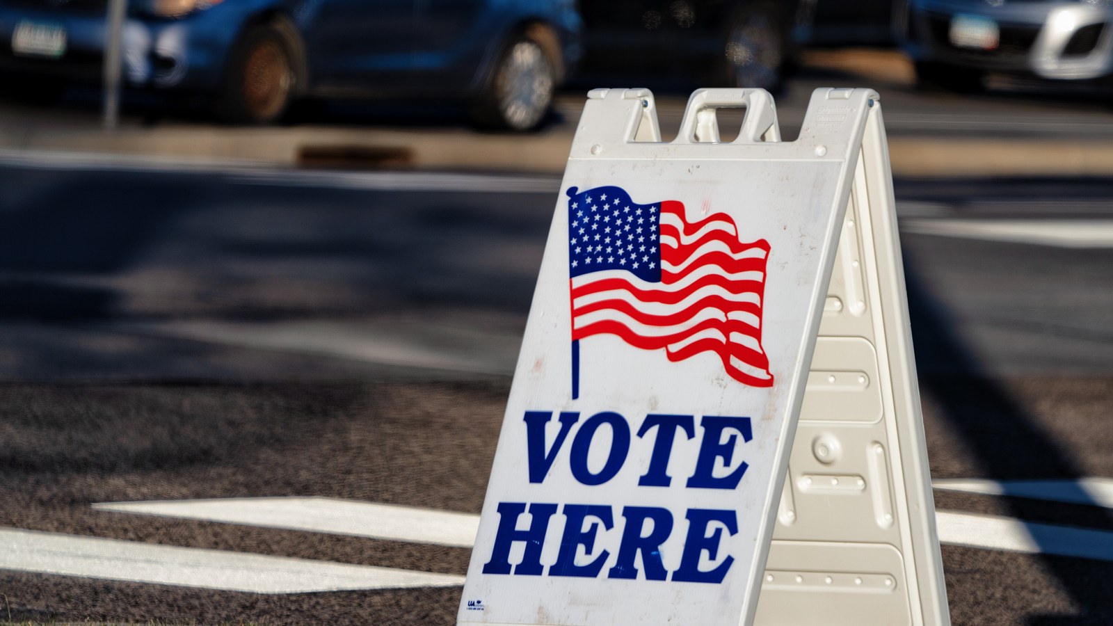 A "Vote Here" sign with an American flag outside a polling place